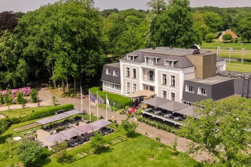 Exterior, sky view of beige and gray hotel building with a garden and patio in front