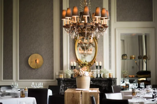 Dining area in a hotel with a chandelier and dining tables in the room