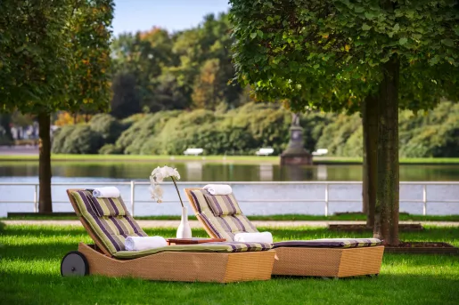 Two reclining chairs on a field of grass, with a lake in the background