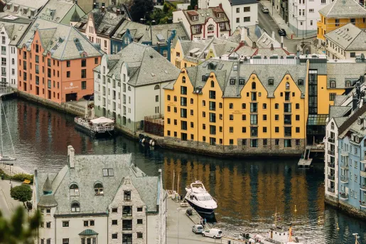 Exterior view of orange and black hotel building, by a river in the middle of a town