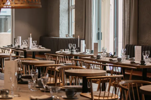 Dining hall with wooden tables and chairs, with wine glasses on each table