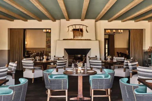 Indoor dining hall with green and gray cushioned chairs and a fireplace in the center