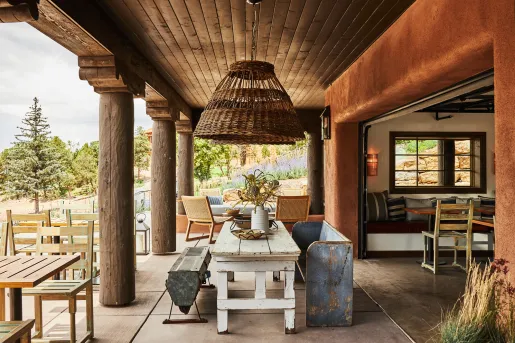 Outdoor patio with wooden chairs and tables, with large wooden pillars on the left