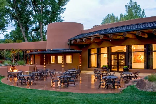 Exterior view of red clay building with dining tables and chairs outdoors