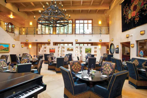 Indoor dining hall with large, blue chairs and a piano to the left