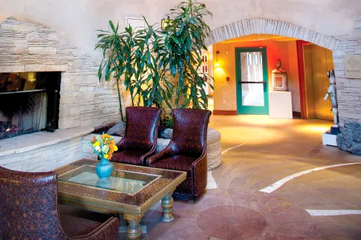 Lobby and seating area with red, leather chairs in front of a stone fireplace