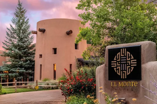 Exterior view of a clay hotel building with a stone "El Monte" sign