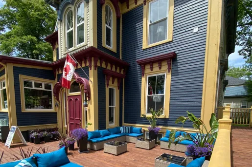 Exterior view of blue and yellow house with a Canadian flag in front