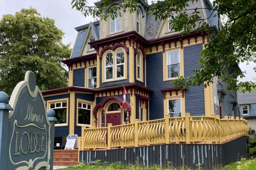Exterior view of blue and yellow hotel building with a yellow gate in front