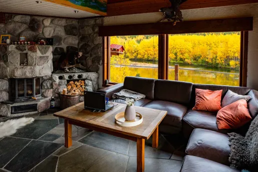 Room with a stone fireplace and leather sofa in front,  with a wooden table in the center