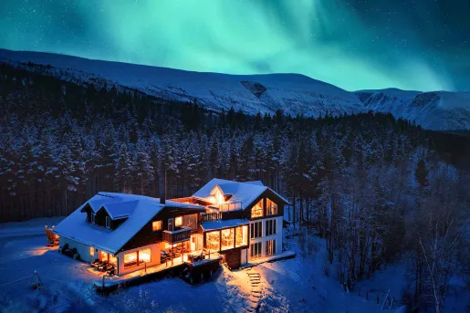 Large cabin-style building with snow and a forest in the background