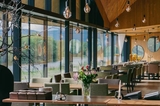 Cafe and seating area with green and gray cushioned chairs, and large windows to the left