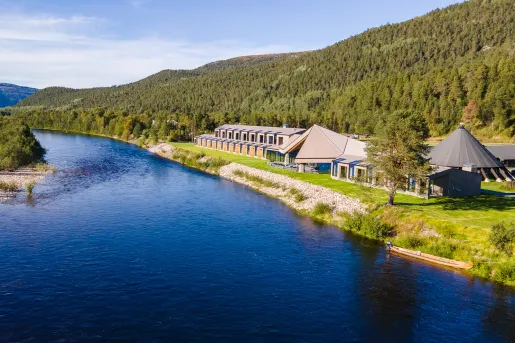 Long building along a river with a forest in the background