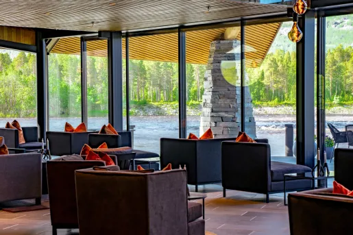 Seating area with cushioned chairs looking out to a river through large glass walls