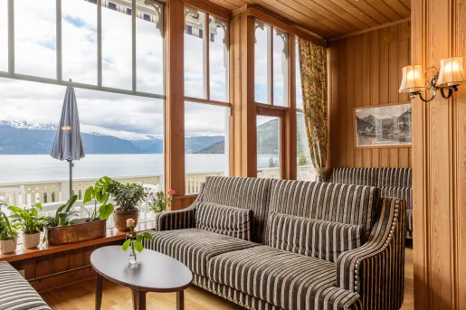 Corner room with wooden walls and striped couches, with a lake outside