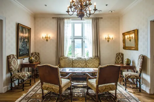 Lounge and seating area with patterned cushioned chairs, with paintings on the walls