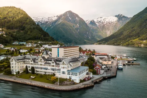Exterior, sky view of a hotel complex with a lake in front and mountains in the background