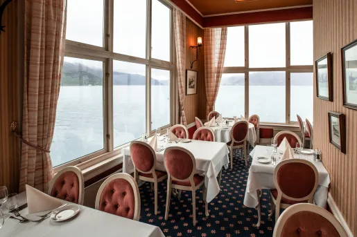 Restaurant in a corner room with large windows, red chairs and white tables