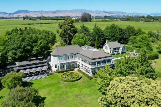 Exterior sky view of white hotel building in the middle of a grassy field