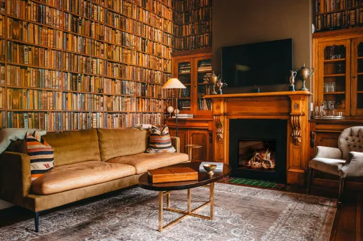 Library room with beige couch and fireplace to the right