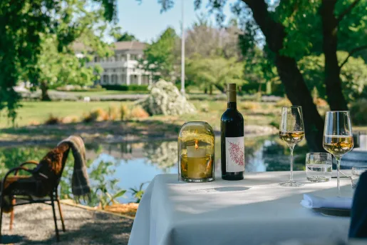 Bottle of wine and wine glasses on a white table looking out towards a lake