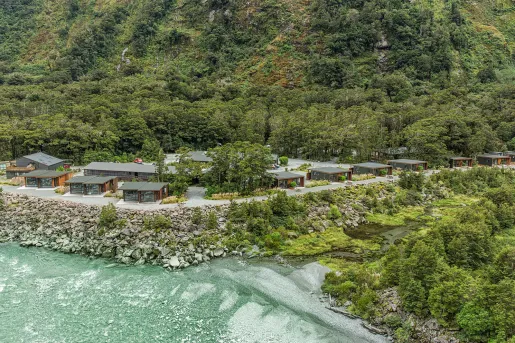Cabin buildings surrounded by thick forest, with the ocean to the left