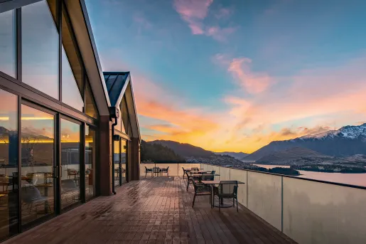 Outdoor balcony and patio, with a building with glass walls on the left and a lake to the right