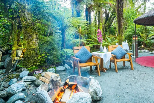 Outdoor camping area with a stone fireplace and two wooden chairs