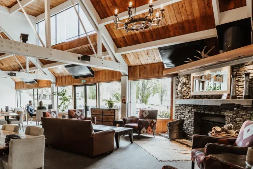 Lodge building's lounge with a stone fireplace and cushioned chairs