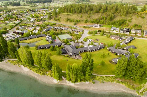 Sky view of hotel complex buildings in the middle of a valley with a small town and tall trees in the background