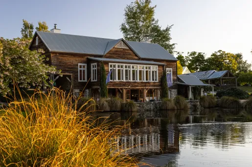 Exterior view of large wooden building with a lake in front