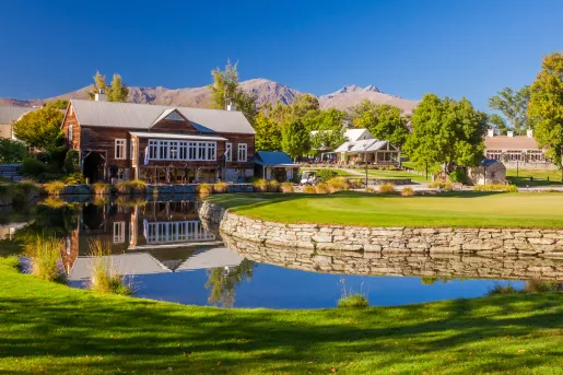 Large grass area with a small pond and a wooden building in the background