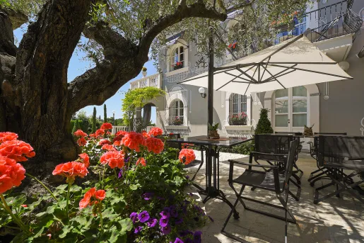 Outdoor patio and garden with black dining tables and chairs, and white umbrellas
