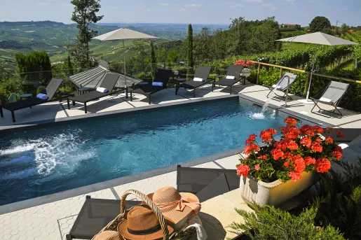 Outdoor pool surrounded by reclining chairs and a valley in the distance