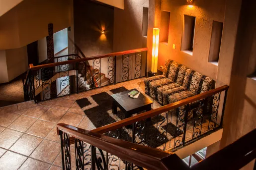 Indoor seating area with staircases on either side, with a patterned couch and black table