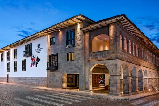 Exterior view of stone hotel building with small archways and empty road in front