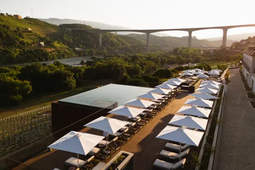 Outdoor patio with a pool, reclining chairs and a view of a tall bridge