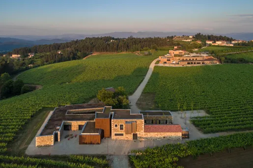 Two large building complexes attached by a dirt trail, in the middle of a crop valley