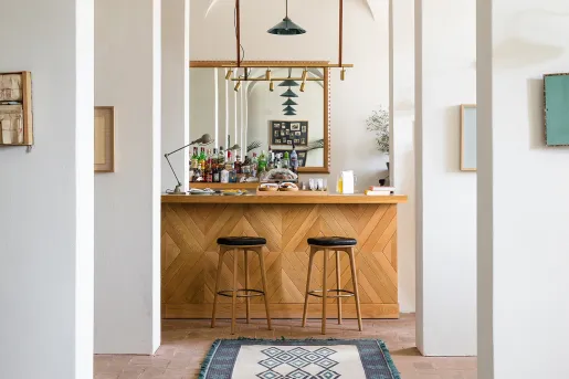 White hallway leading to a bar counter and two wooden stools