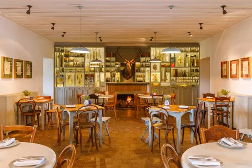 Dining area with wooden tables and chairs, with a deer head hanging on the wall