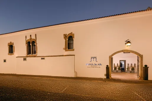 Exterior view of large, white building with gold window coverings and a large gate