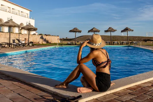Woman sitting on an outdoor pool looking out towards the sky