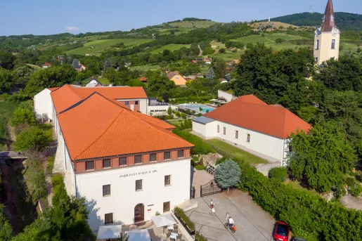 Exterior sky view of large white hotel buildings with red roofing, and a valley in the background