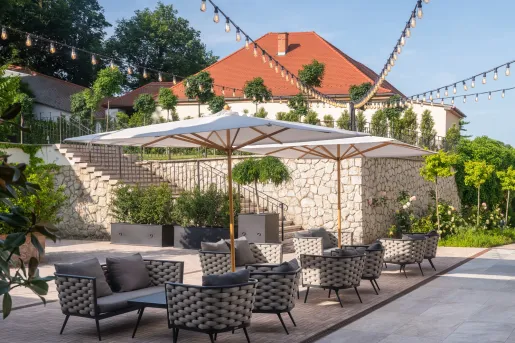 Outdoor patio with cushioned chairs, with a large stone staircase in the background