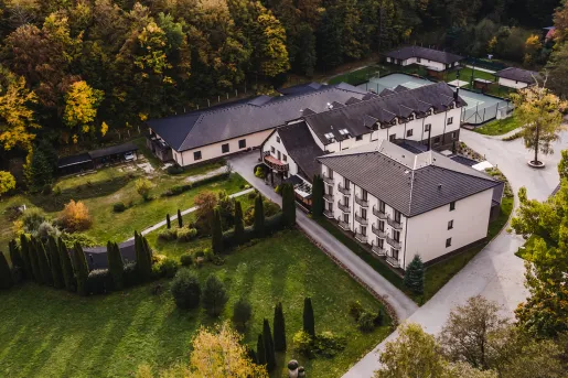 Exterior, sky view of a white hotel building with a forest in the background