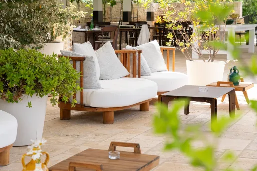 Outdoor patio with white, cushioned chairs and small wooden tables