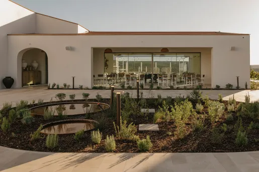 Outdoor view of white building with large windows and an outdoor courtyard and plants