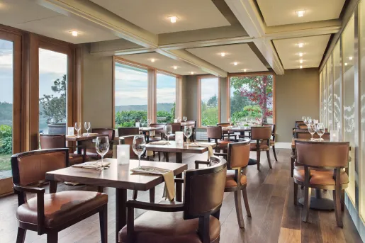 Dining hall with wooden tables and leather chairs, with wine glasses on each table