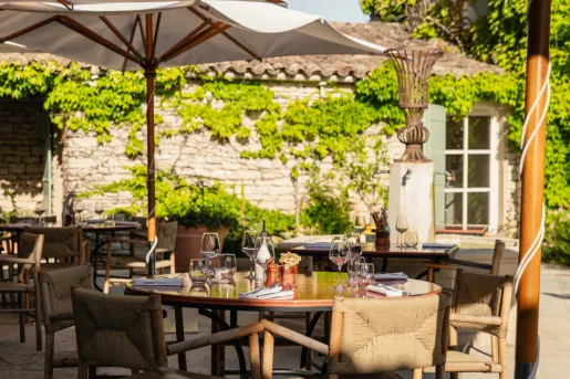 Outdoor patio with dining tables and umbrellas, with wine glasses on each table