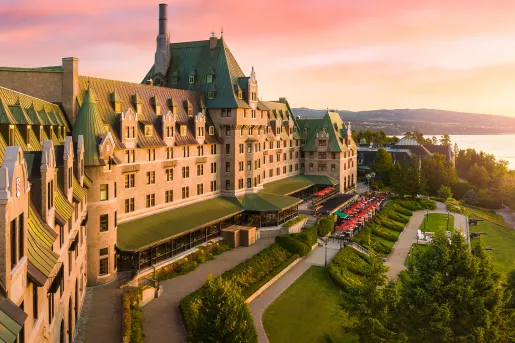 Exterior view of multi-story hotel building with green roofing, and large grass fields in front